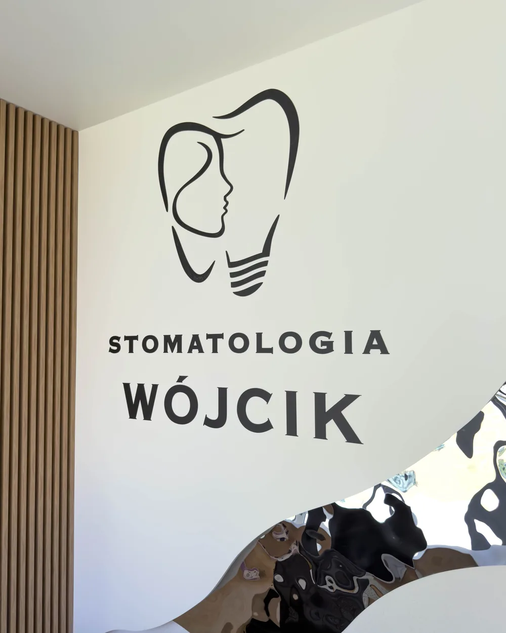 Logo Stomatologia Wójcik na ścianie z drewnianych listew